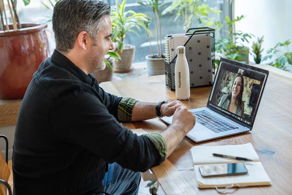 Afbeelding van een persoon die een video gesprek voert achter een laptop.